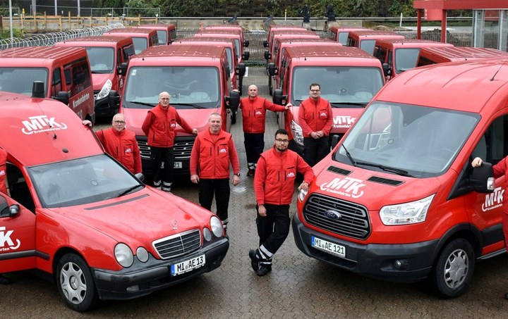 Das Team von MTK vor der Fahrzeugflotte