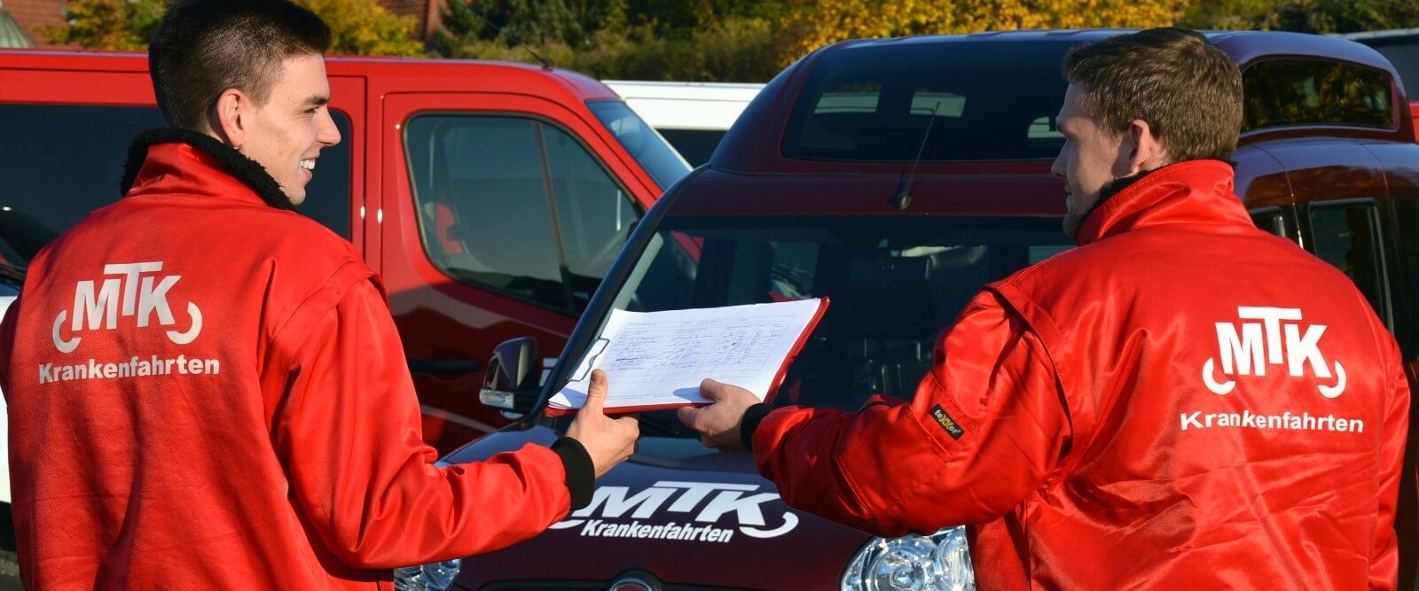 Zwei Fahrer von MTK stimmen sich vor der Abfahrt am Fahrzeug ab