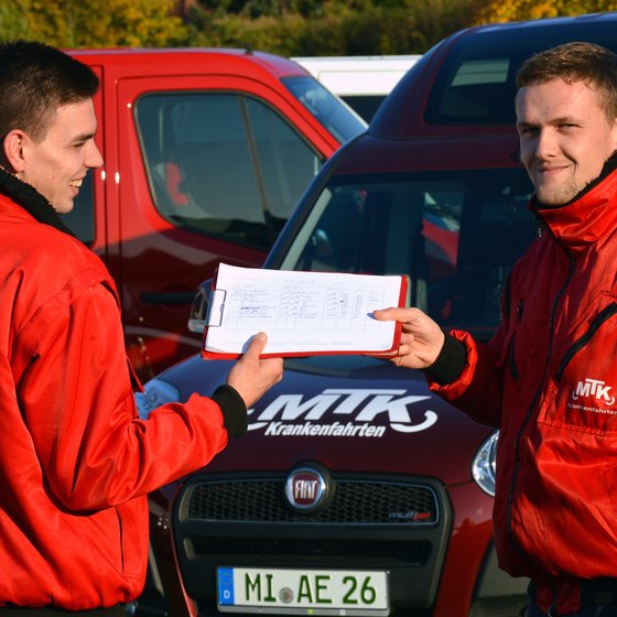 Zwei Fahrer von MTK übergeben einander die Unterlagen für eine Fahrt
